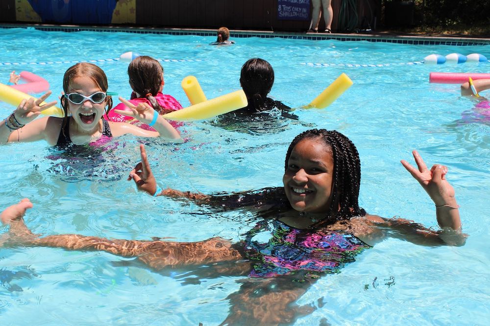Campers in pool showing peace signs