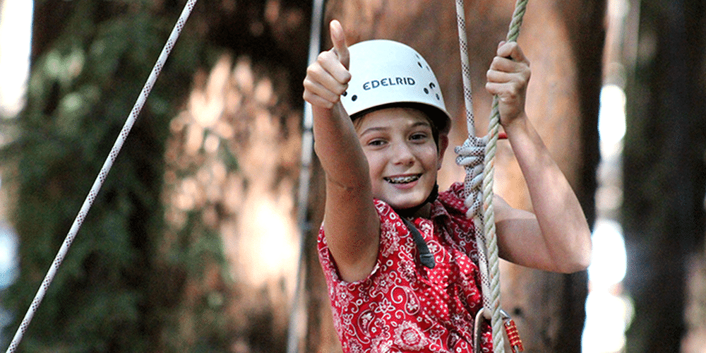 Camper on ropes course giving thumbs up