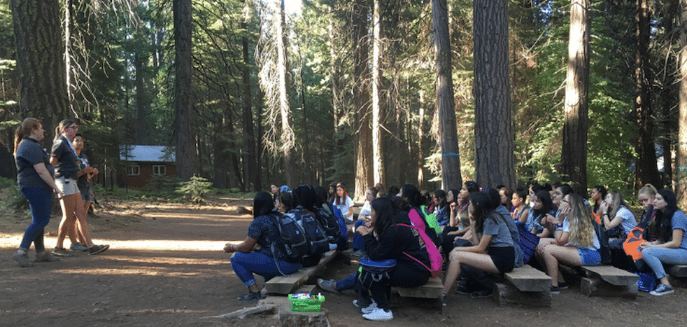 Large group of campers sitting in the woods